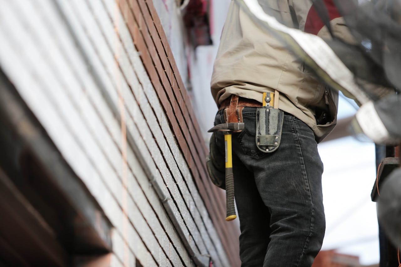 About Close-up of a construction worker with hammer and tools, focused on the job.